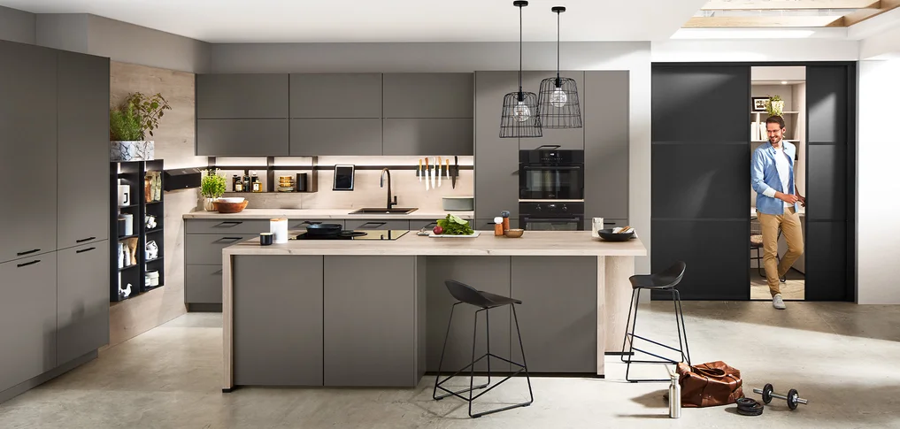 Cuisine ouverte avec porte coulissante intégrée pour des transitions fluides entre la cuisine, le travail et le salon. Moderne et flexible.