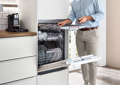 Geöffneter Geschirrspüler in moderner Einbauküche. Der Oberkorb wird bequem beladen. Elegantes Küchendesign mit integrierter Spülmaschine auf ergonomischer Höhe.