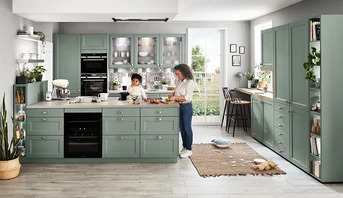 Moderne interpretatie van een keuken in landelijke stijl in saliegroen met open schappen en kookeiland.