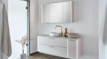 Salle de bains moderne et lumineuse, avec un éclairage vertical sur l'armoire de toilette et un meuble sous-vasque éclairé.