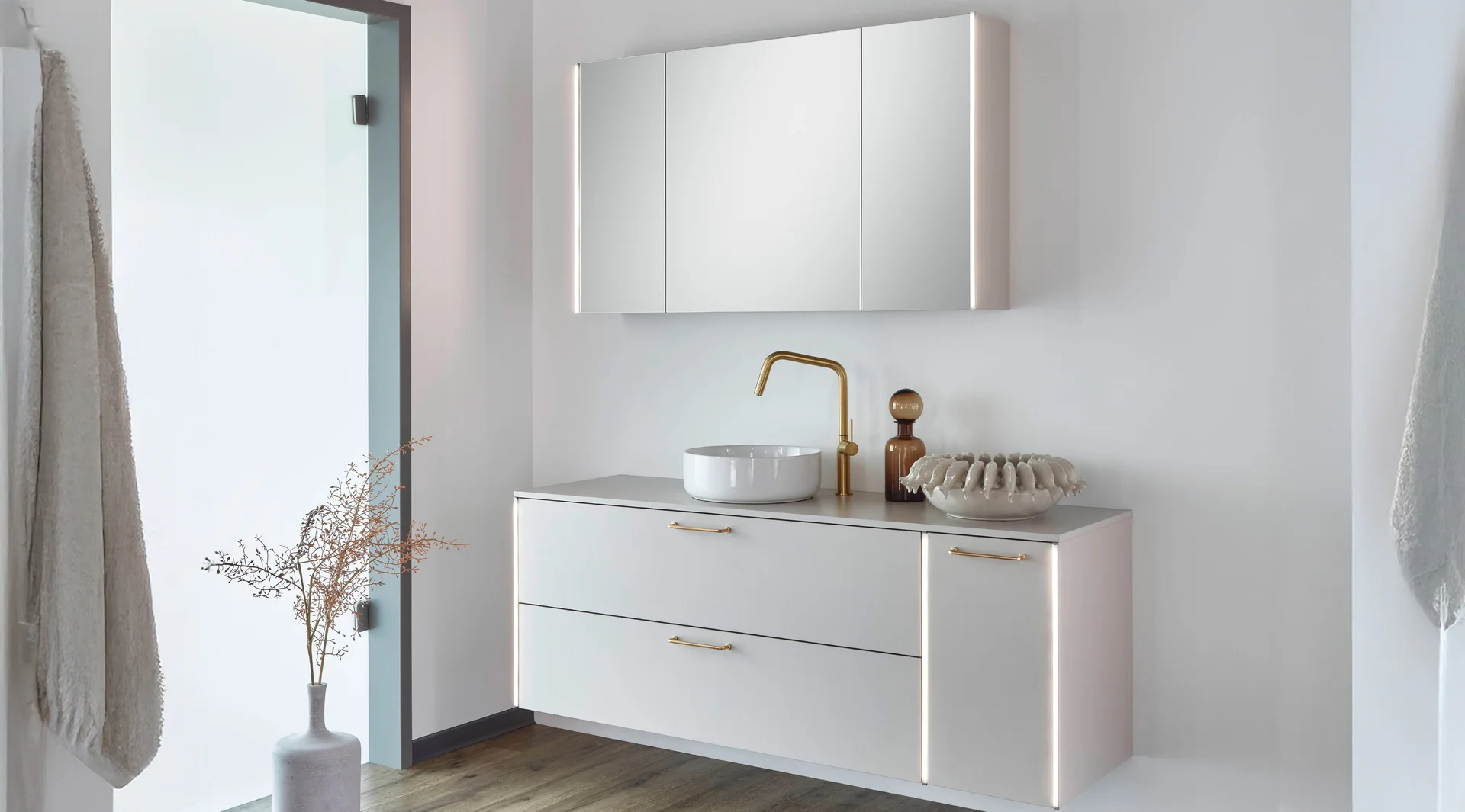 Salle de bains moderne et lumineuse, avec un éclairage vertical sur l'armoire de toilette et un meuble sous-vasque éclairé.
