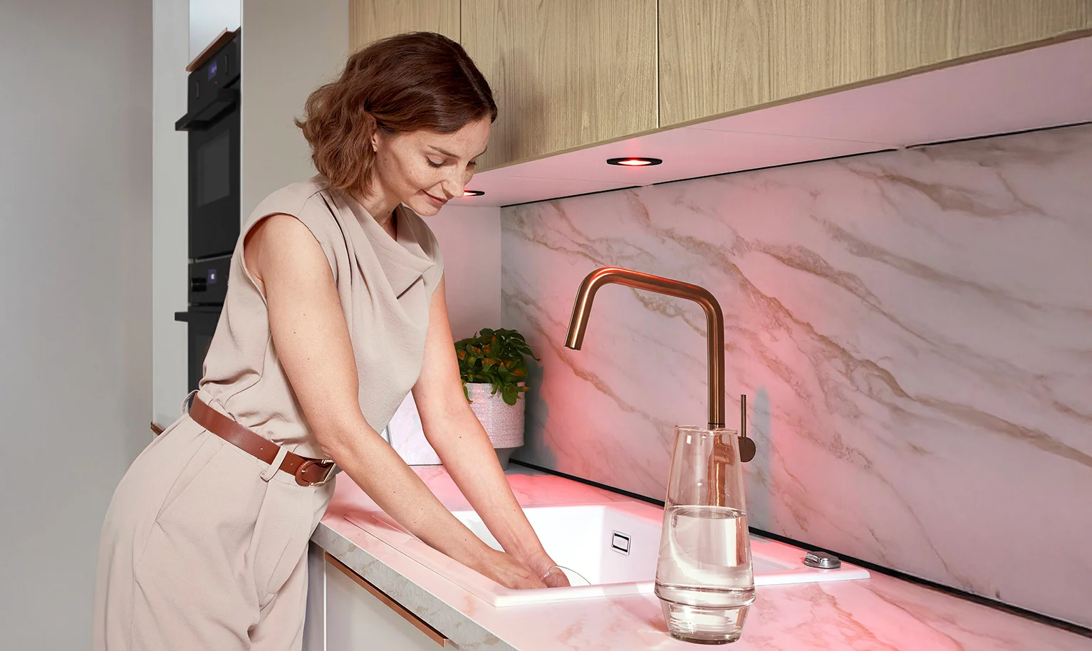 Fond d'évier ergonomique dans la cuisine - femme près de l'évier avec les coudes positionnés légèrement au-dessus du plan de travail.
