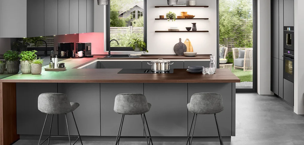 Cuisine moderne avec des placards gris, un plan de travail en bois et d'élégants tabourets de bar au premier plan.