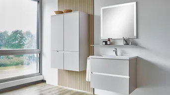 Salle de bains avec éclairage intégré dans les poignées encastrées du meuble sous-lavabo et miroir éclairé, dans un design clair.