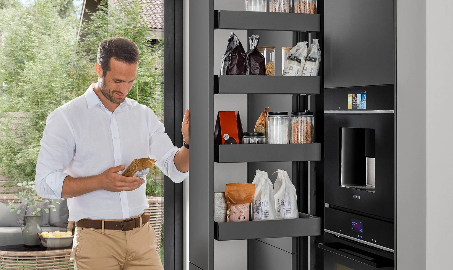 Cuisine moderne et ergonomique avec armoire à pharmacie - l'homme utilise l'espace de rangement accessible des deux côtés pour un accès rapide et confortable.