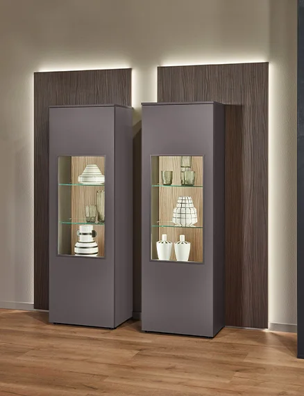 Vitrine éclairée dans le salon avec insert en verre, paroi arrière en bois et éclairage LED indirect.