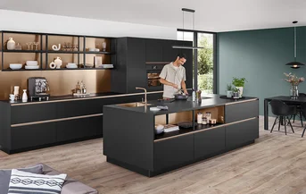 Moderne Küche mit Fronten in Schwarz Premium matt aus dem Programm SENSO 496 und goldfarbenen Akzenten im offenen Regalbereich.