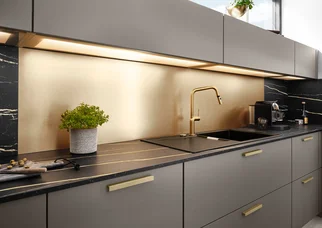 Fond lumineux à LED pour l'éclairage de la cuisine, avec une crédence de couleur bronze au-dessus d'un plan de travail foncé.