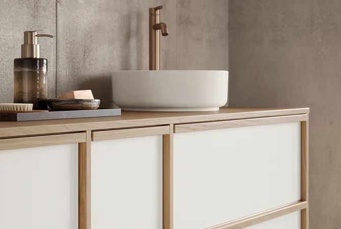 Mobili da bagno eleganti in look Japandi con rubinetto color bronzo e accessori armoniosi in look cornice di legno.