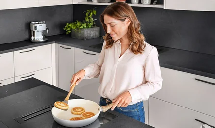 Cuisiner sur la table de cuisson avec hotte intégrée - une solution ergonomique pour plus d'espace pour la tête.