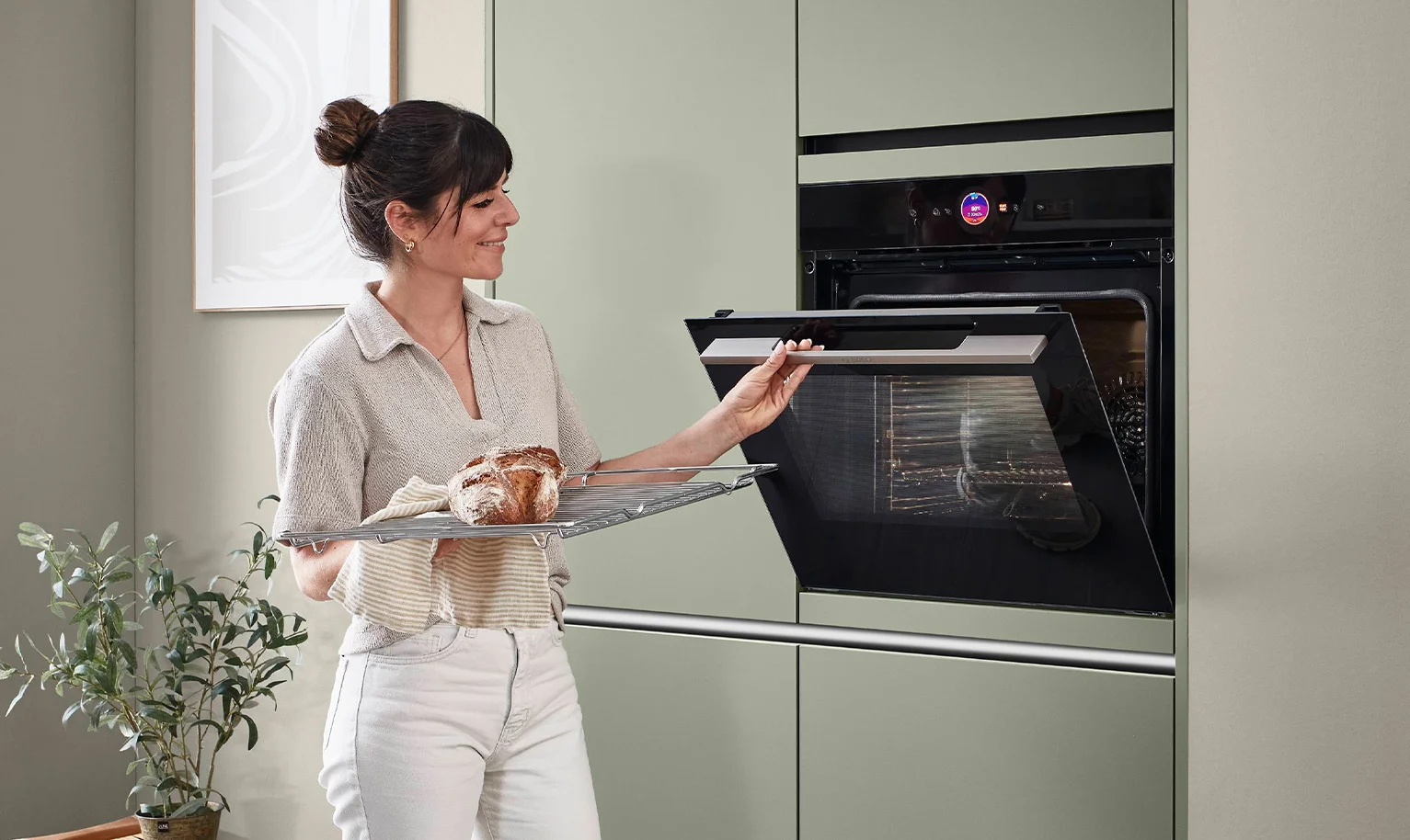 Femme devant le four à hauteur d'accès dans une cuisine ergonomique - utilisation confortable et ménageant le dos