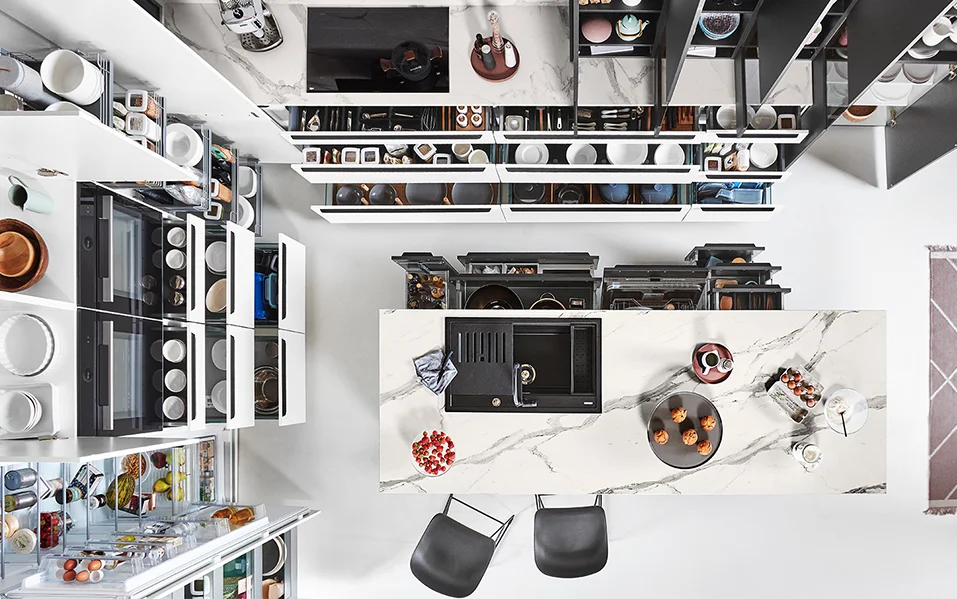 L-vormige keuken met marmeren werkblad, efficiënt opbergconcept en volledig open uittrekelementen, gefotografeerd vanuit vogelperspectief.